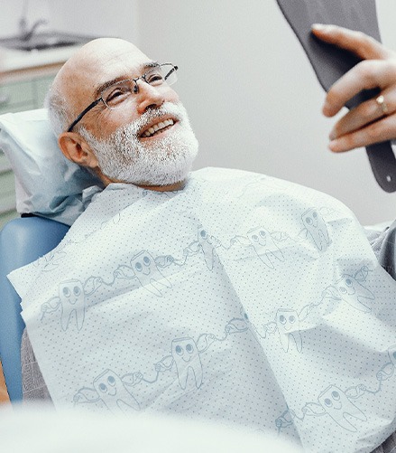 Patient smiling at reflection in handheld mirror