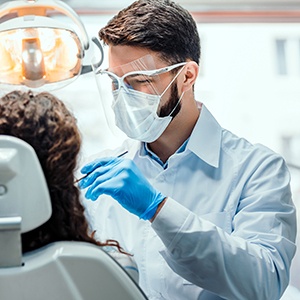 Dentist examining patient's teeth in treatment room