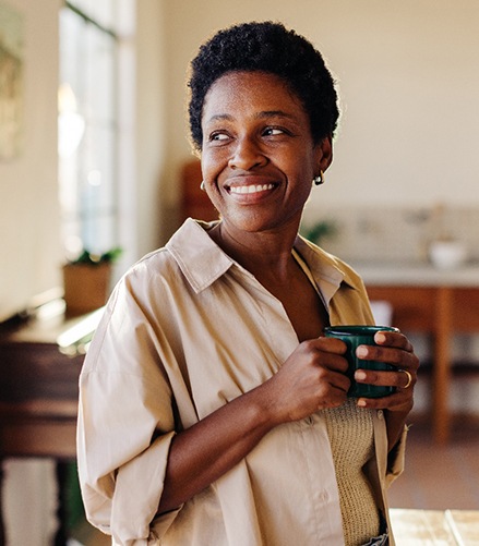Woman smiling while enjoying cup of tea at home
