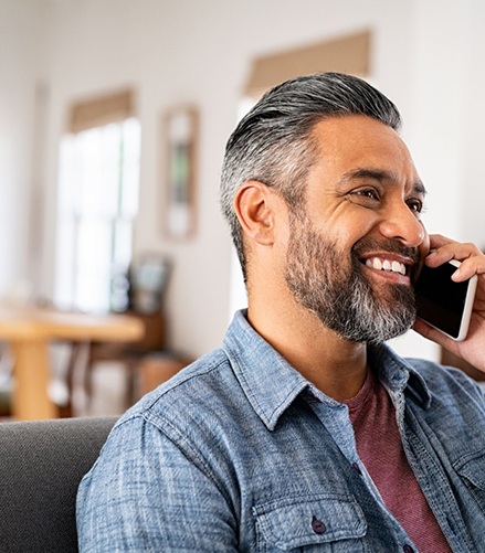 Man smiling while talking on phone at home