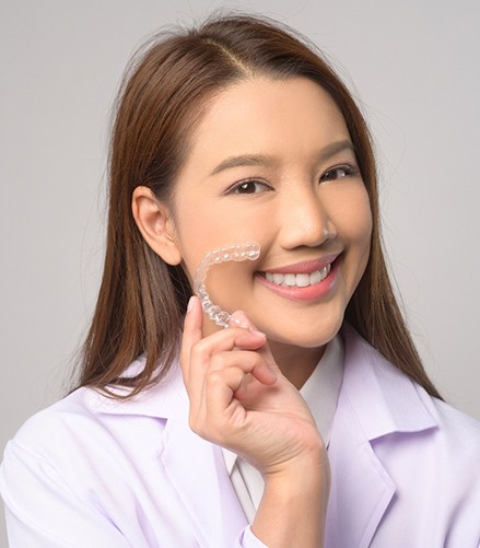 Smiling patient holding clear aligner