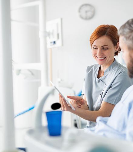 Smiling dentist showing patient image on tablet