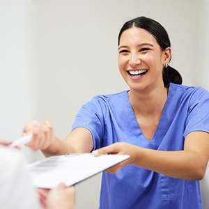 a woman in scrubs handing a patient forms