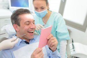 Man looking at his cosmetic dentistry results in mirror