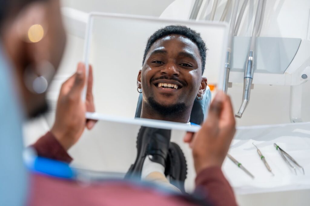 A man looking at his smile in the mirror after cosmetic dentistry treatment