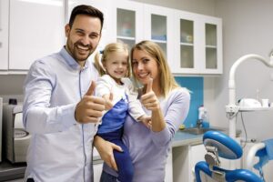 Family at the dentist holding thumbs up